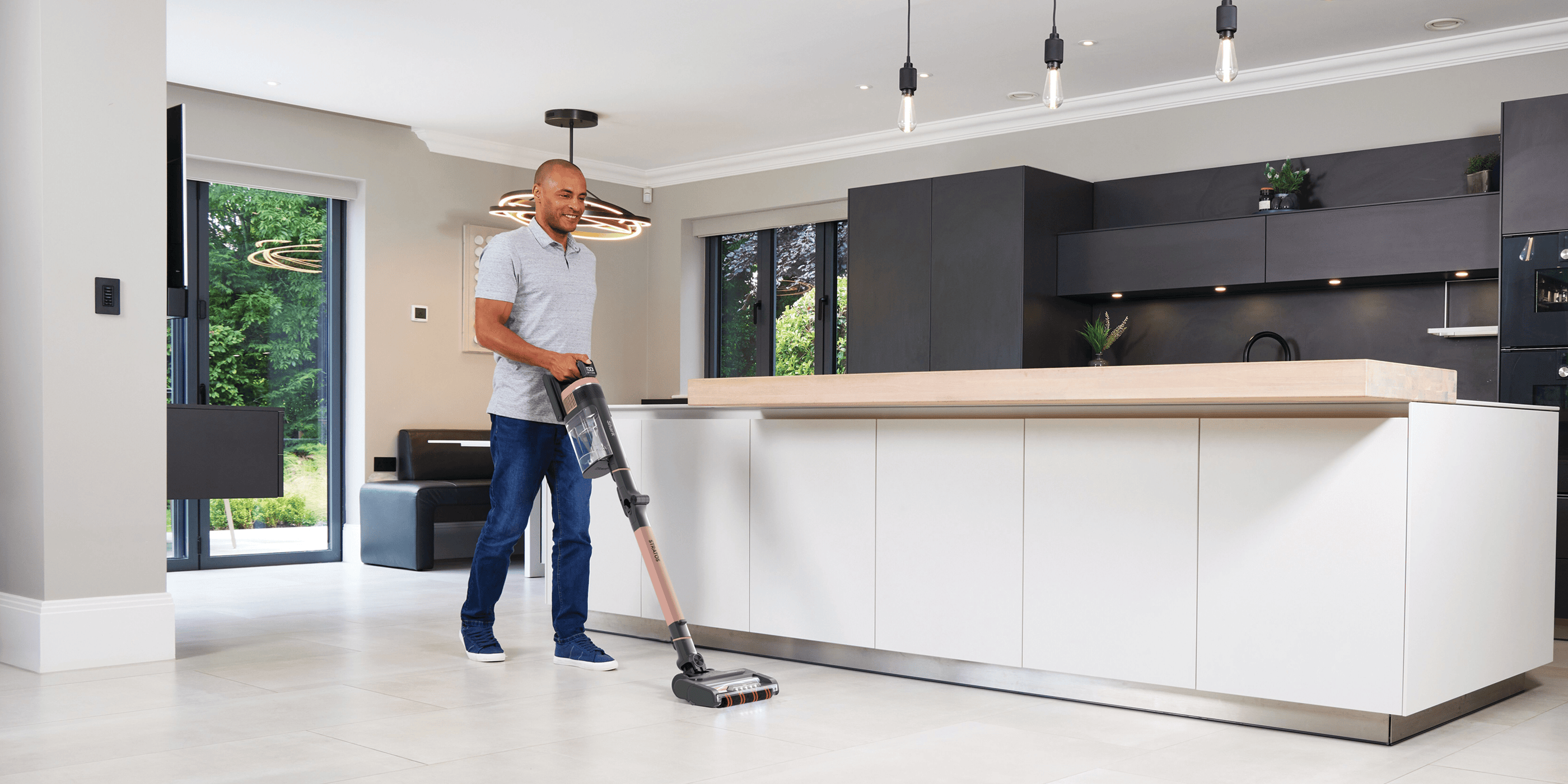 Vacuum cleaner being used in a modern living room, with a dog sitting on the carpet