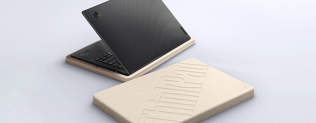 Lenovo ThinkPad X1 Carbon laptop with carbon fiber weave, lid partially open, seen from the rear-right view with two plastic-free packaging pieces