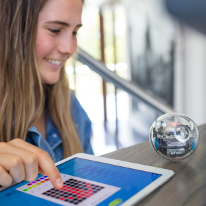 Girl smiling and coding Sphero BOLT STEM robot toy with an ipad.