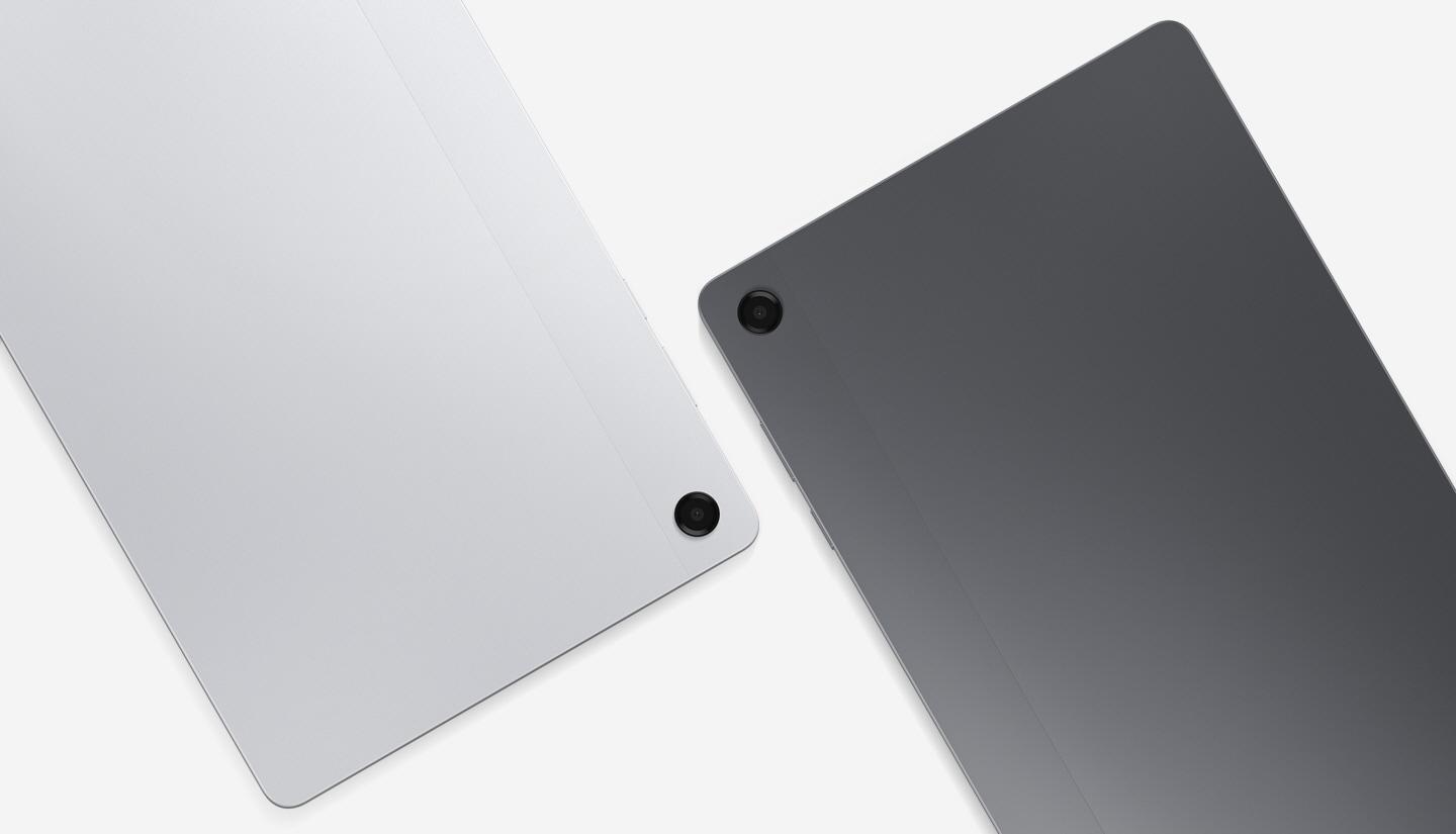 Two Galaxy Tab A11+ tablets are placed side by side, one grey and one silver, with their backs facing the viewer. The back camera lenses of both tablets are visible.